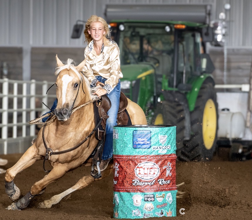 A barrel racer and her horse turning a barrel